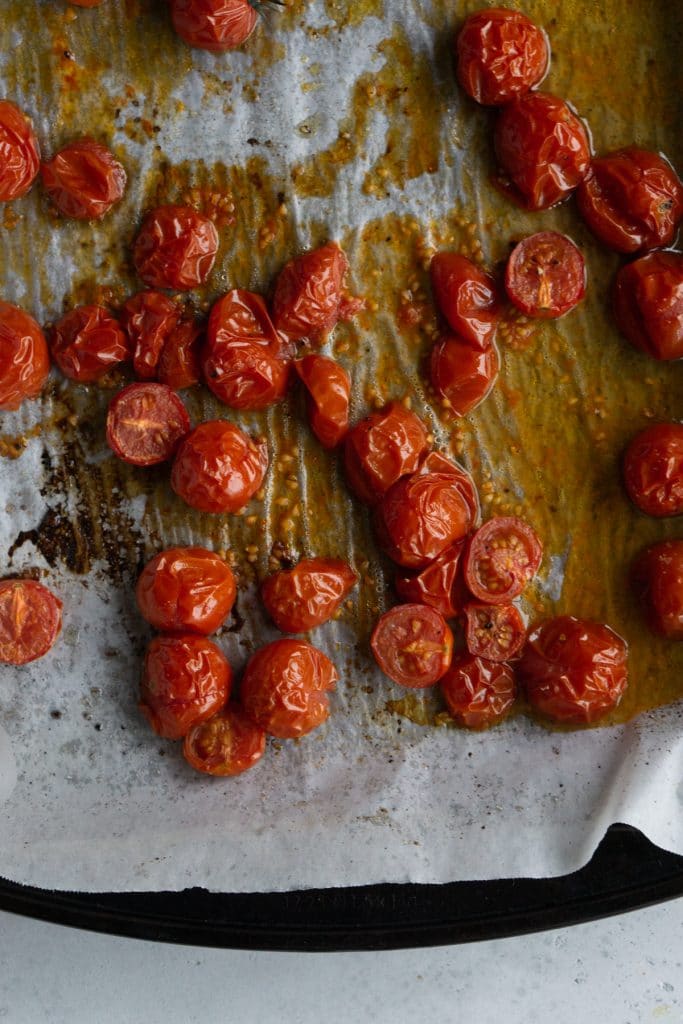 Roasted tomatoes on a parchment lined baking sheet