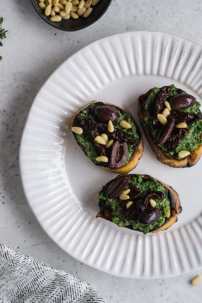 Three pesto crostini on a white plate