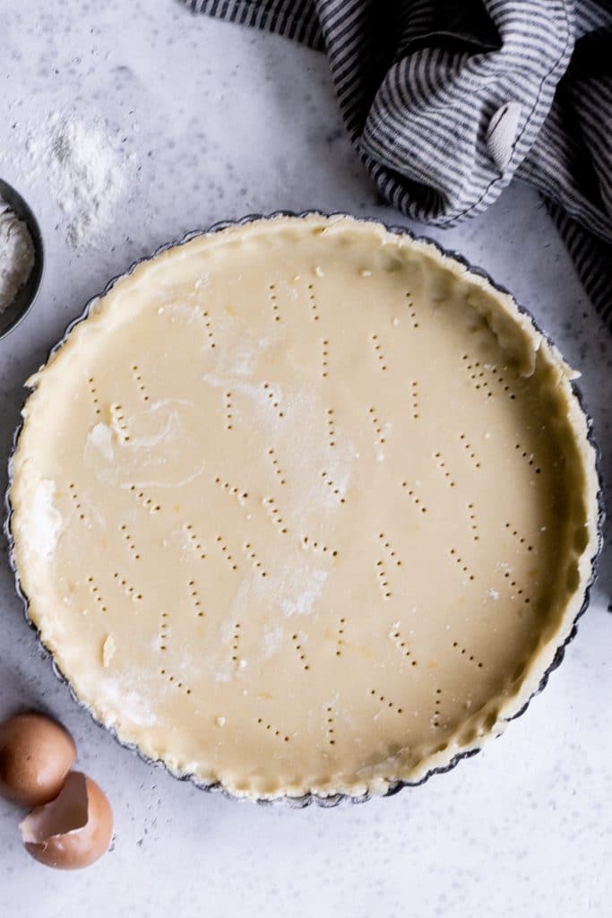 Pasta frolla in a tart pan with a napkin to the side