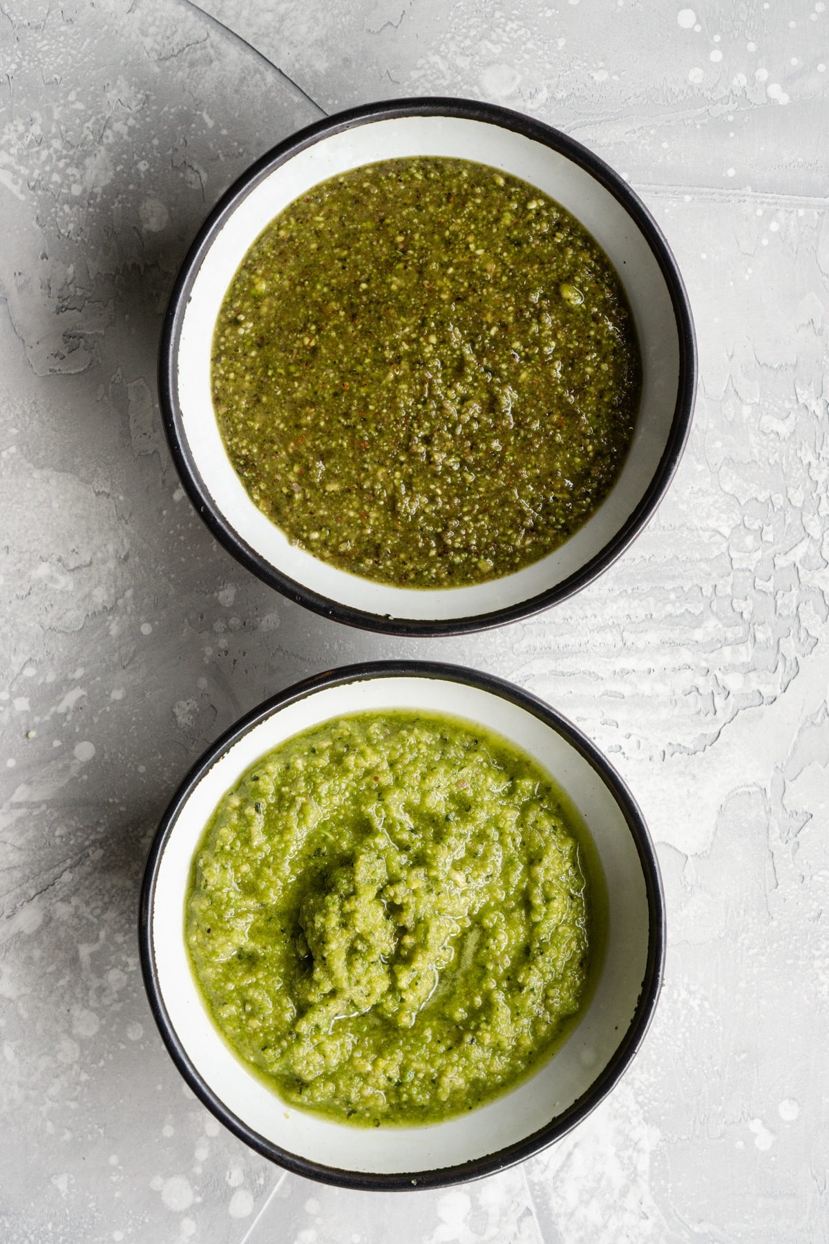 Two bowls of pistachio pesto - one using regular pistachios and one using peeled pistachios