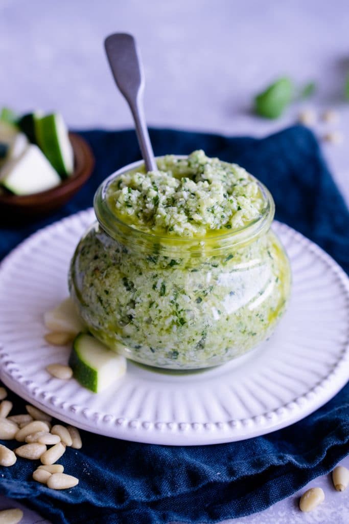 Jar of zucchini pesto with a spoon in the jar