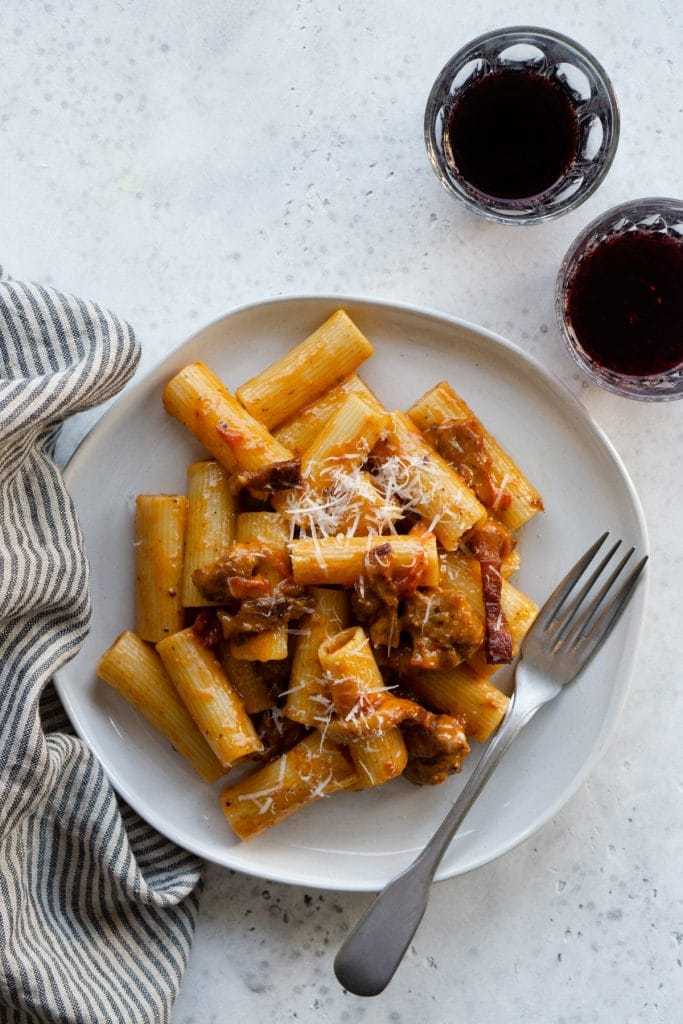 Zozzona pasta on a white plate with a fork and a napkin on the side