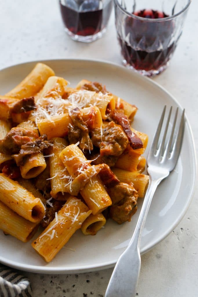 Side view of zozzona pasta on a white plate with a fork