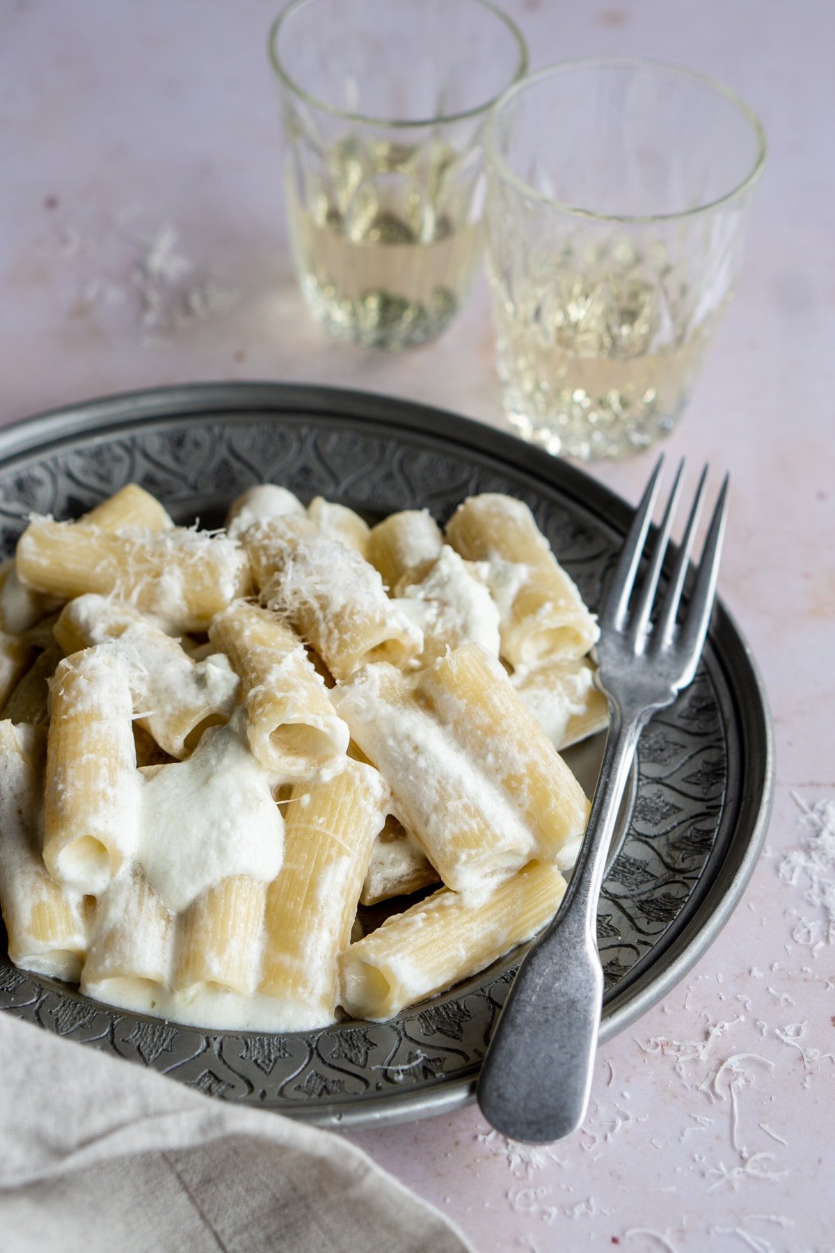 Ricotta pasta in a dish with 2 wine glasses in the background