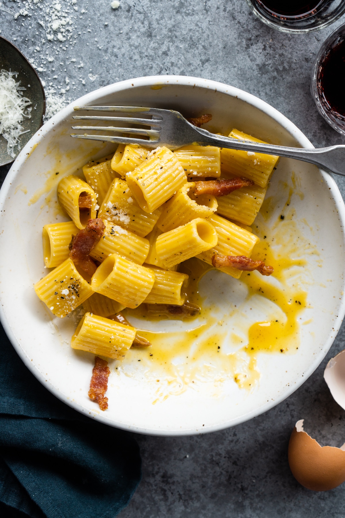 bowl of half eaten carbonara with guanciale strips