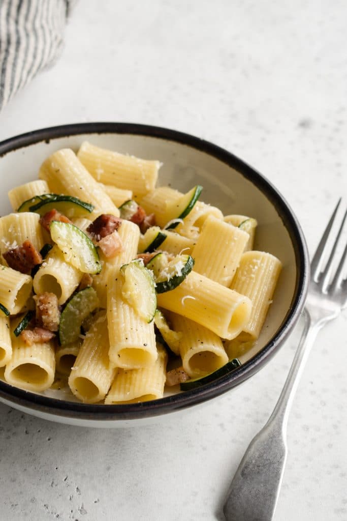 Zucchini and pancetta pasta in a white bowl