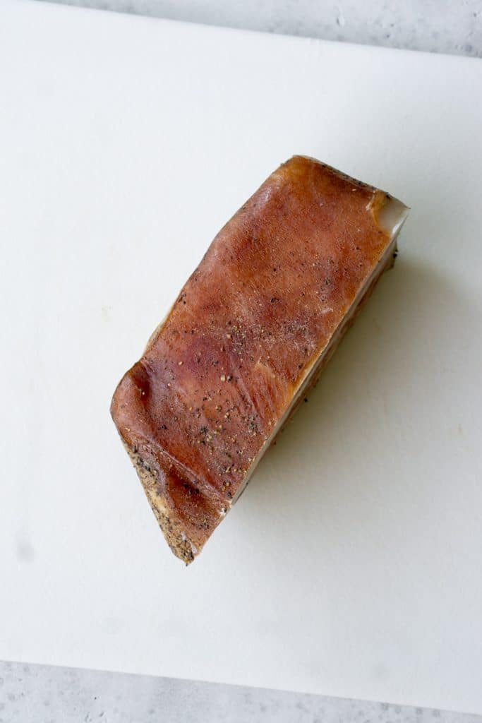 Full piece of guanciale on a cutting board with skin side up