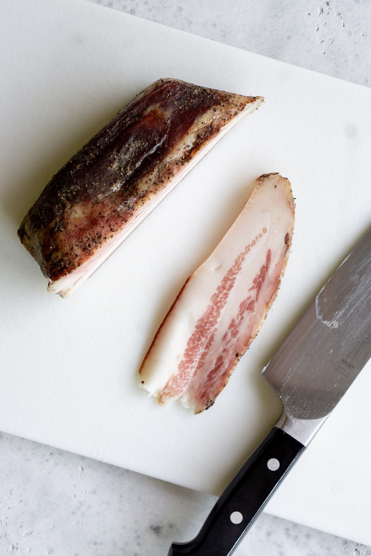 Knife on cutting board and piece of sliced guanciale