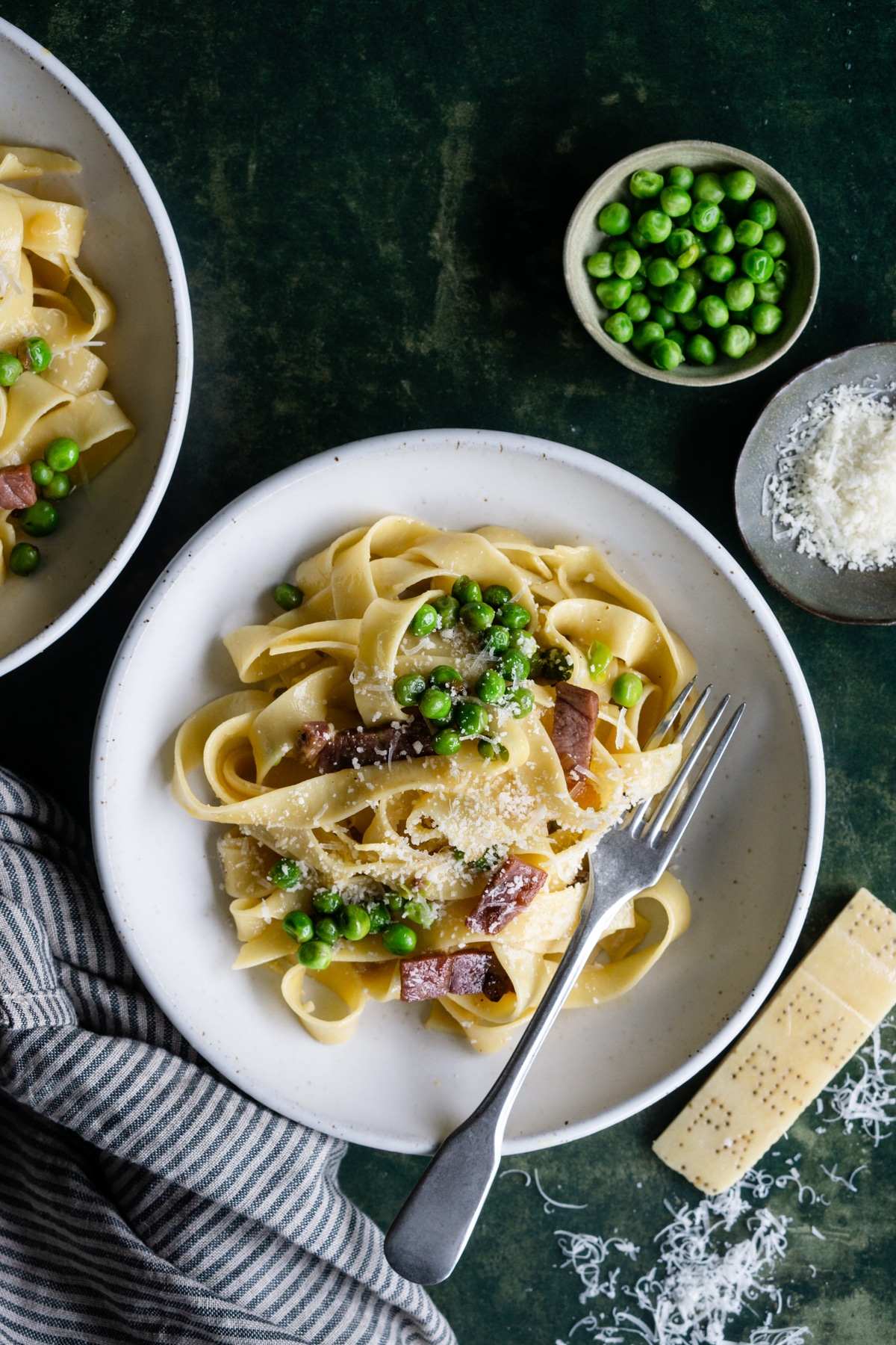 Papalina pasta in a bowl with a small bowl of peas and parmigiano reggiano on the side