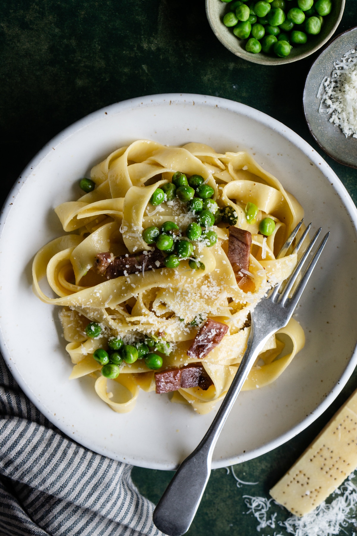 Bowl of pasta alla papalina with a fork in it and a parmigiano reggiano rind to the side
