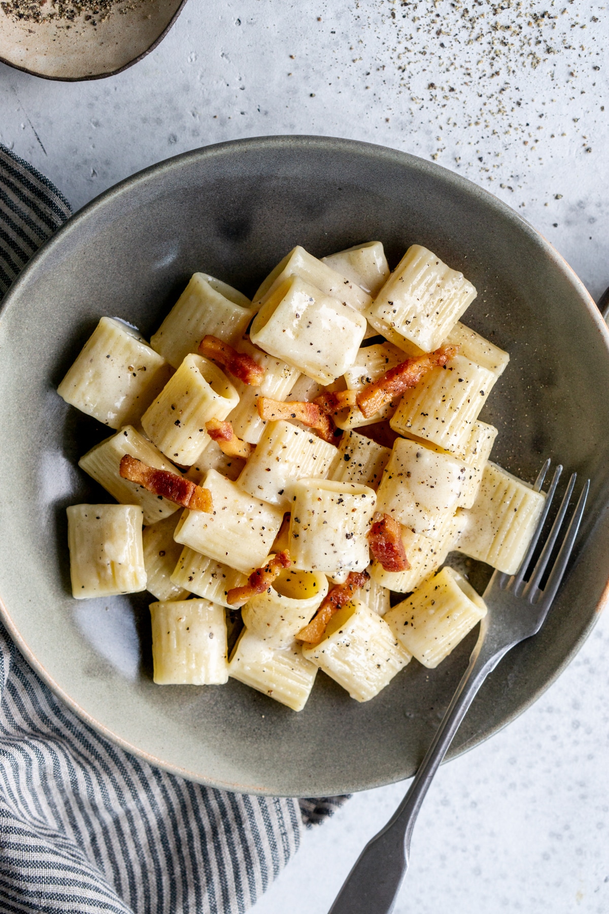 Pasta alla gricia in a gray bowl on a napkin