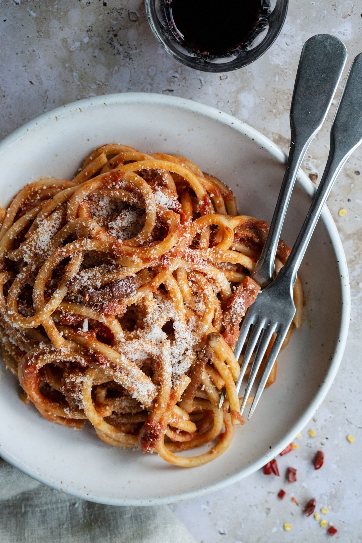 Bowl of pasta amatriciana topped wth pecorino romano with two forks in it