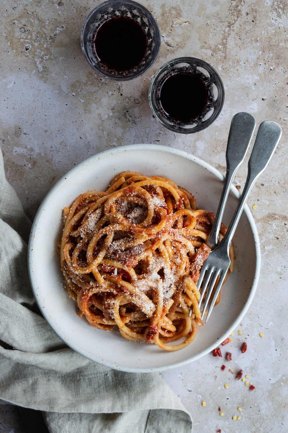 Pasta amatriciana in a bowl with a napkin and hot chili peppers on the side