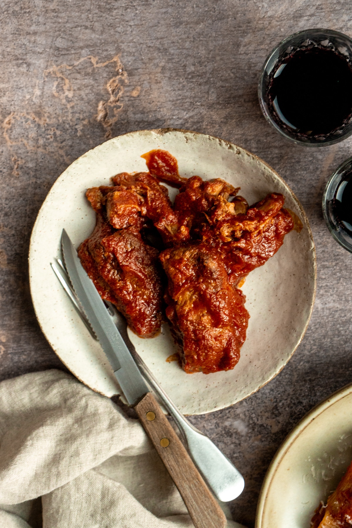 Braised pork ragu in a plate with a fork and knife to the side