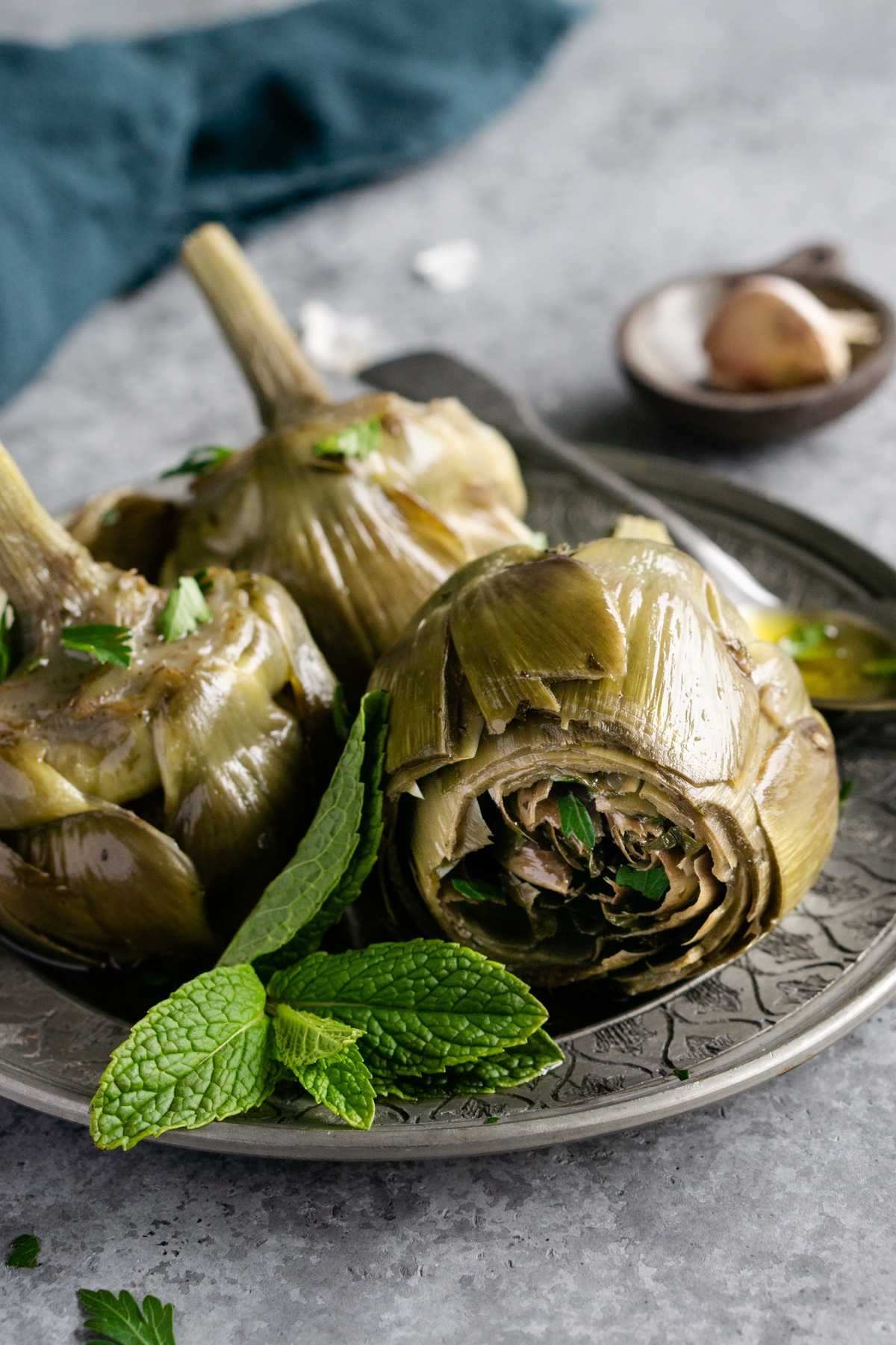 roman artichokes (carciofi alla romana) in a dish with a bunch of mint