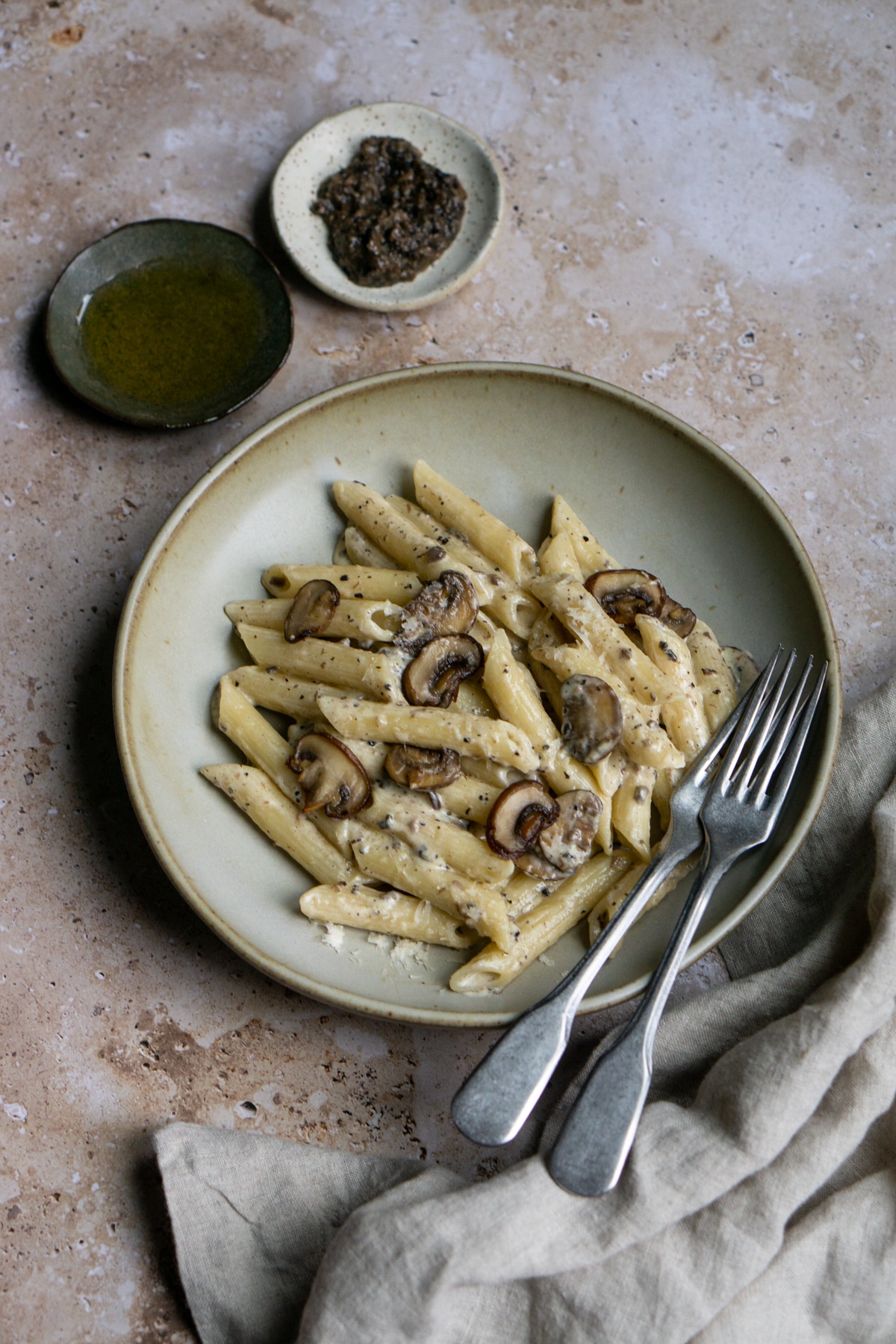 Plate of creamy mushroom pasta with olive oil and mushroom puree in the background