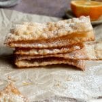 Chiacchiere stacked on top of each other on a piece of parchment paper