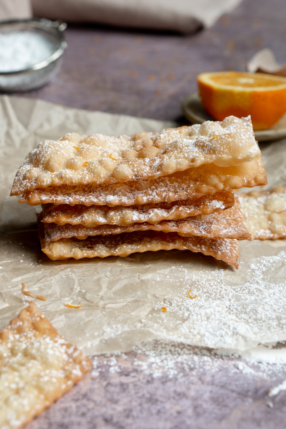 Chiacchiere stacked on top of each other on a piece of parchment paper