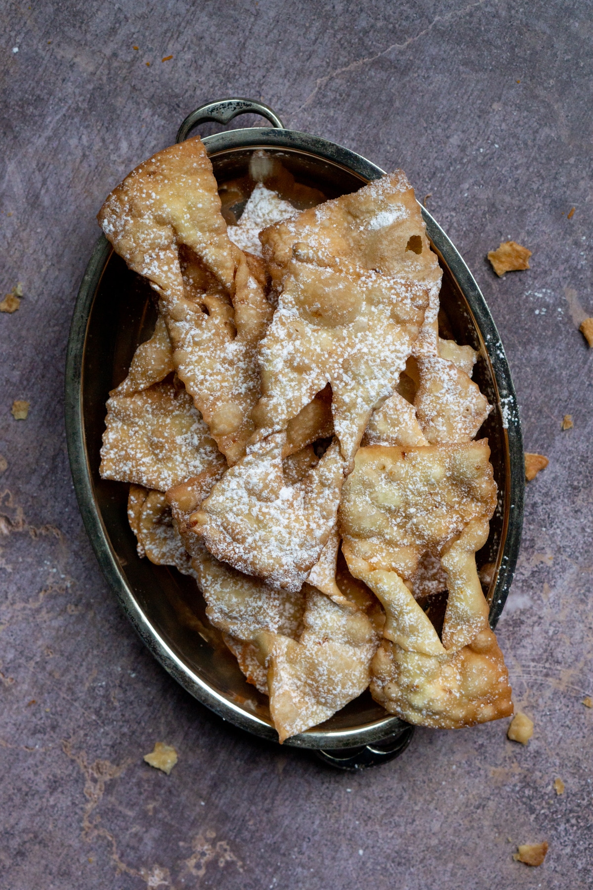 Overhead photo of chicacchiere in a serving tray with crumbs strewn around