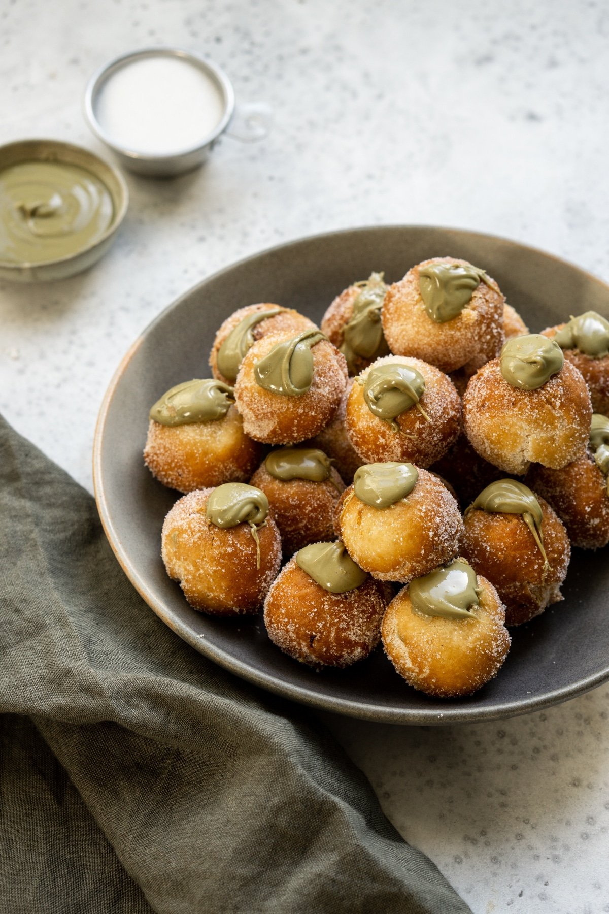 Pistachio castagnole in a plate with pistachio cream in the background