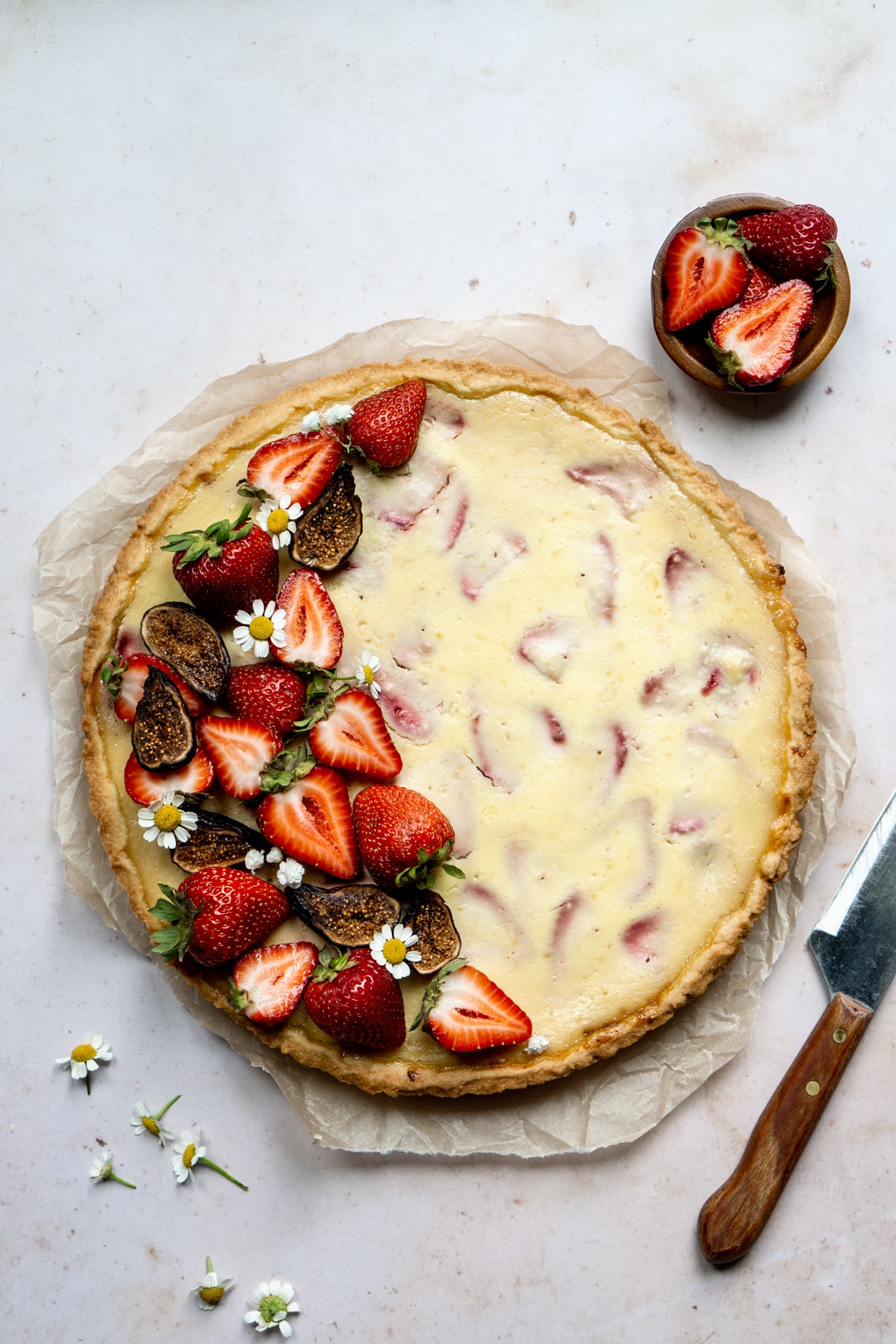 Strawberry and ricotta crostata topped with fresh strawberries, dried figs and small flowers