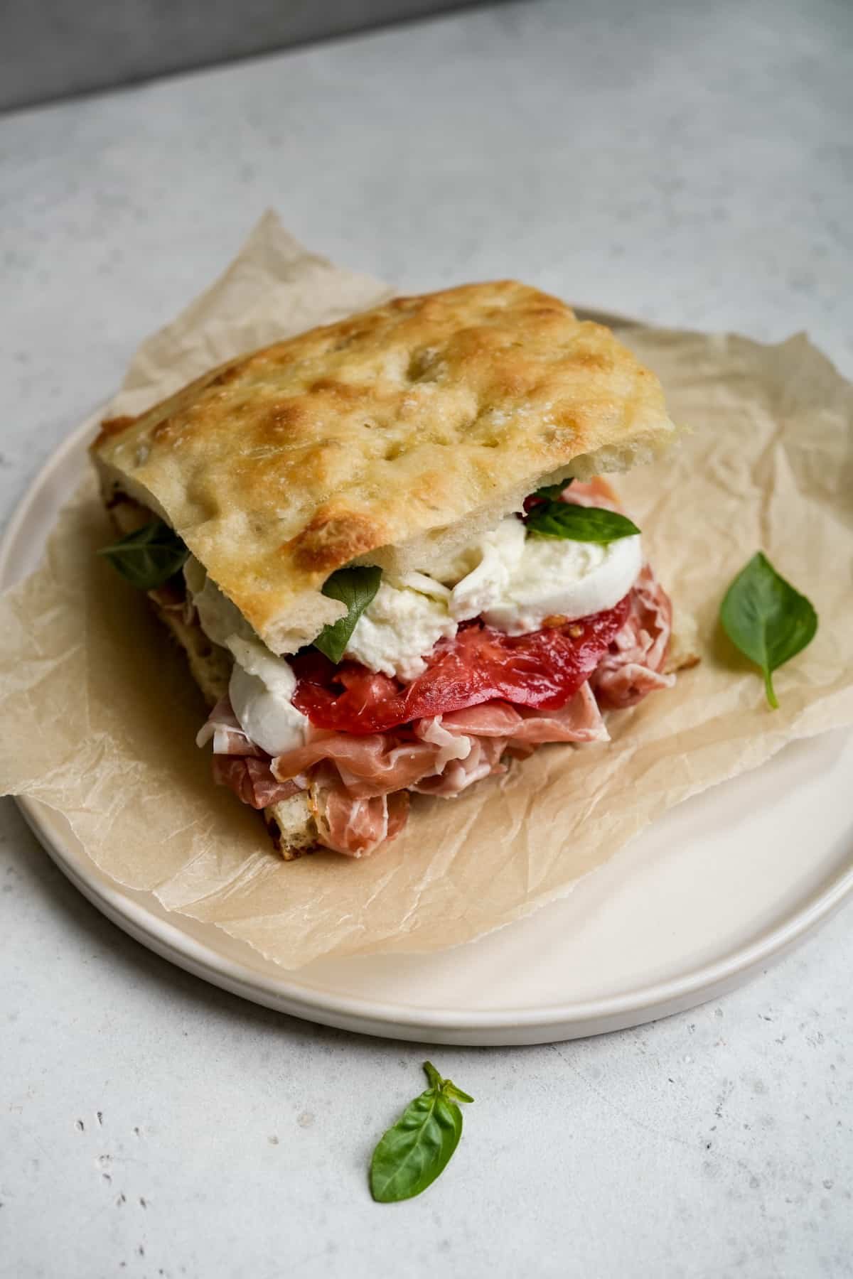 Prosciutto panino with mozzarella, tomato and basil on a plate