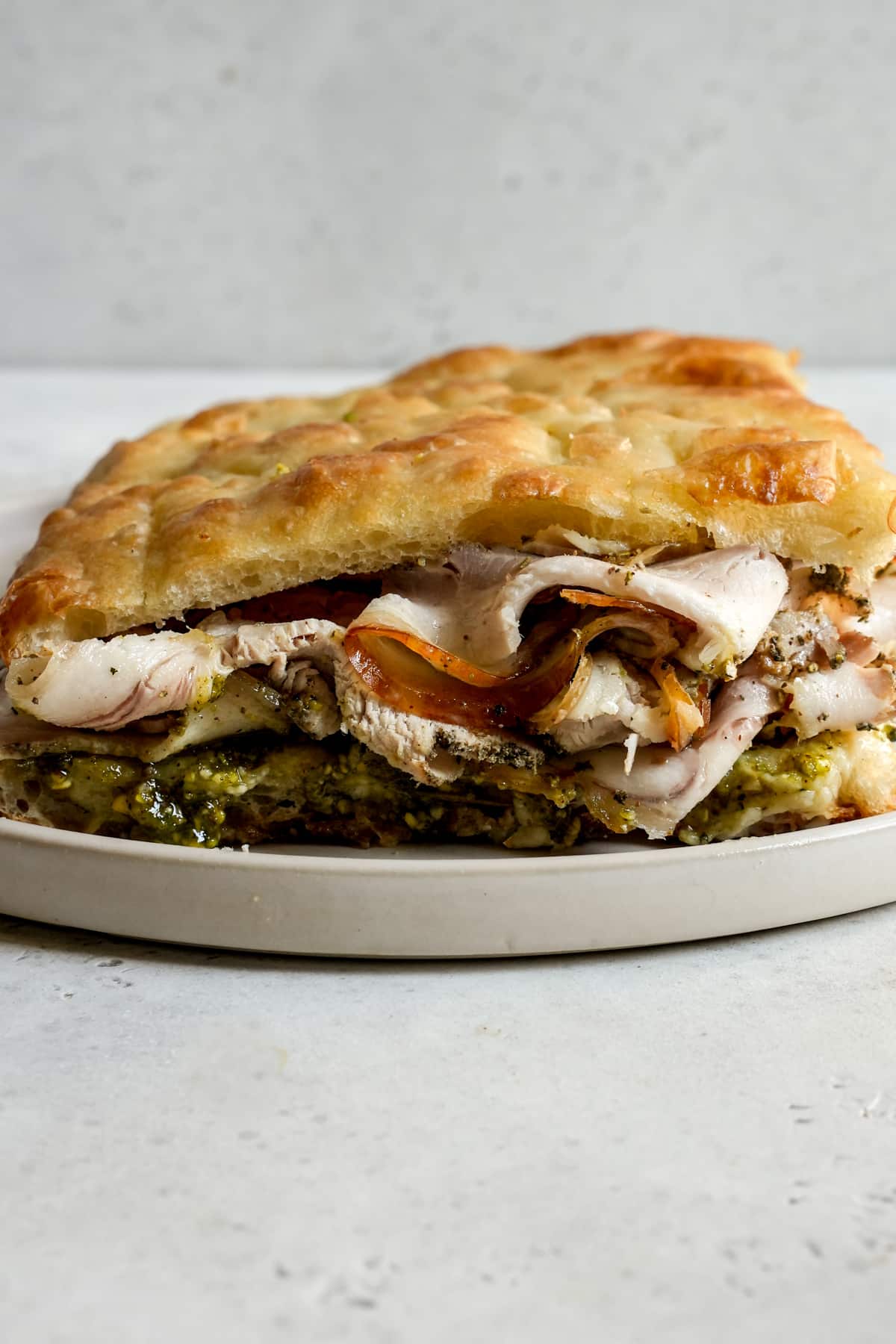 Porchetta panino with gorgonzola and pistachio pesto on a plate