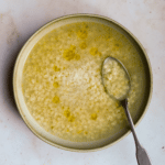 chicken pastina soup in a bowl topped with olive oil and parmesan