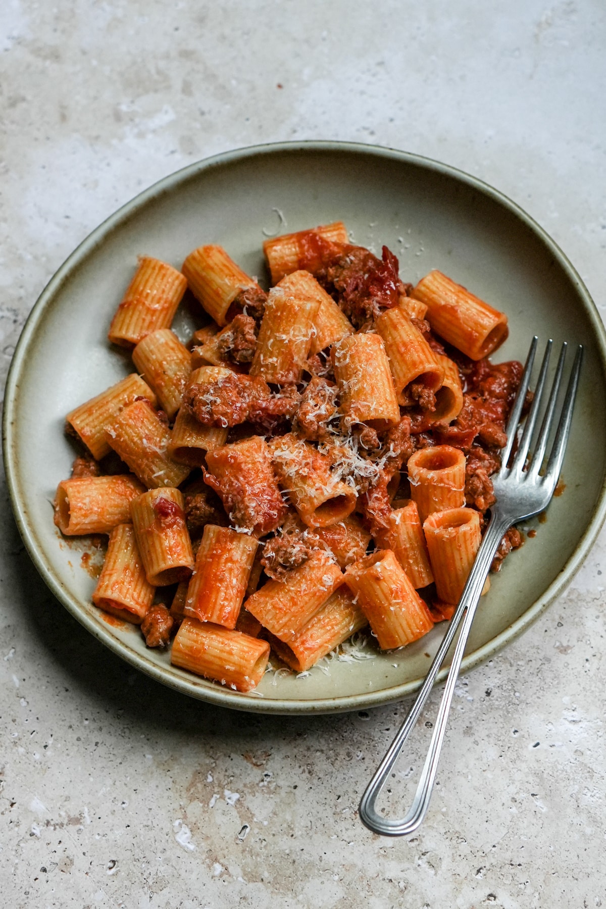 Spicy sausage pasta in a bowl topped with parmesan cheese