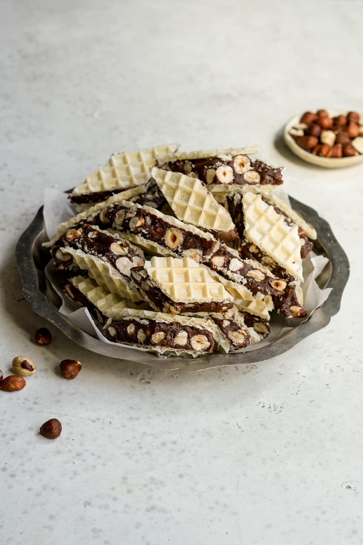 Marshmallow torrone recipe in a serving dish with a small bowl of hazelnuts in the background