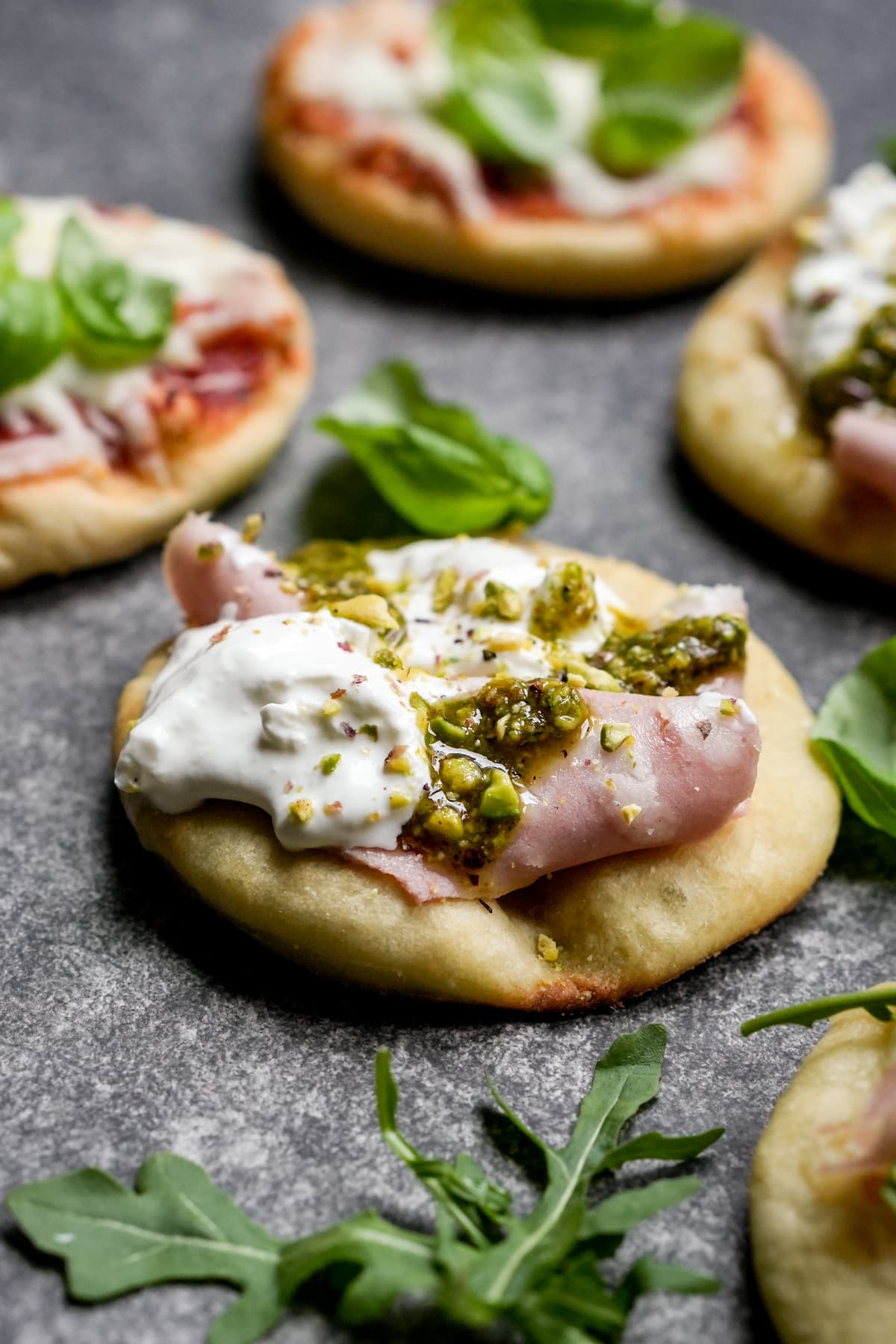 Mini pizzetta topped with mortadella, burrata, and pistachio pesto