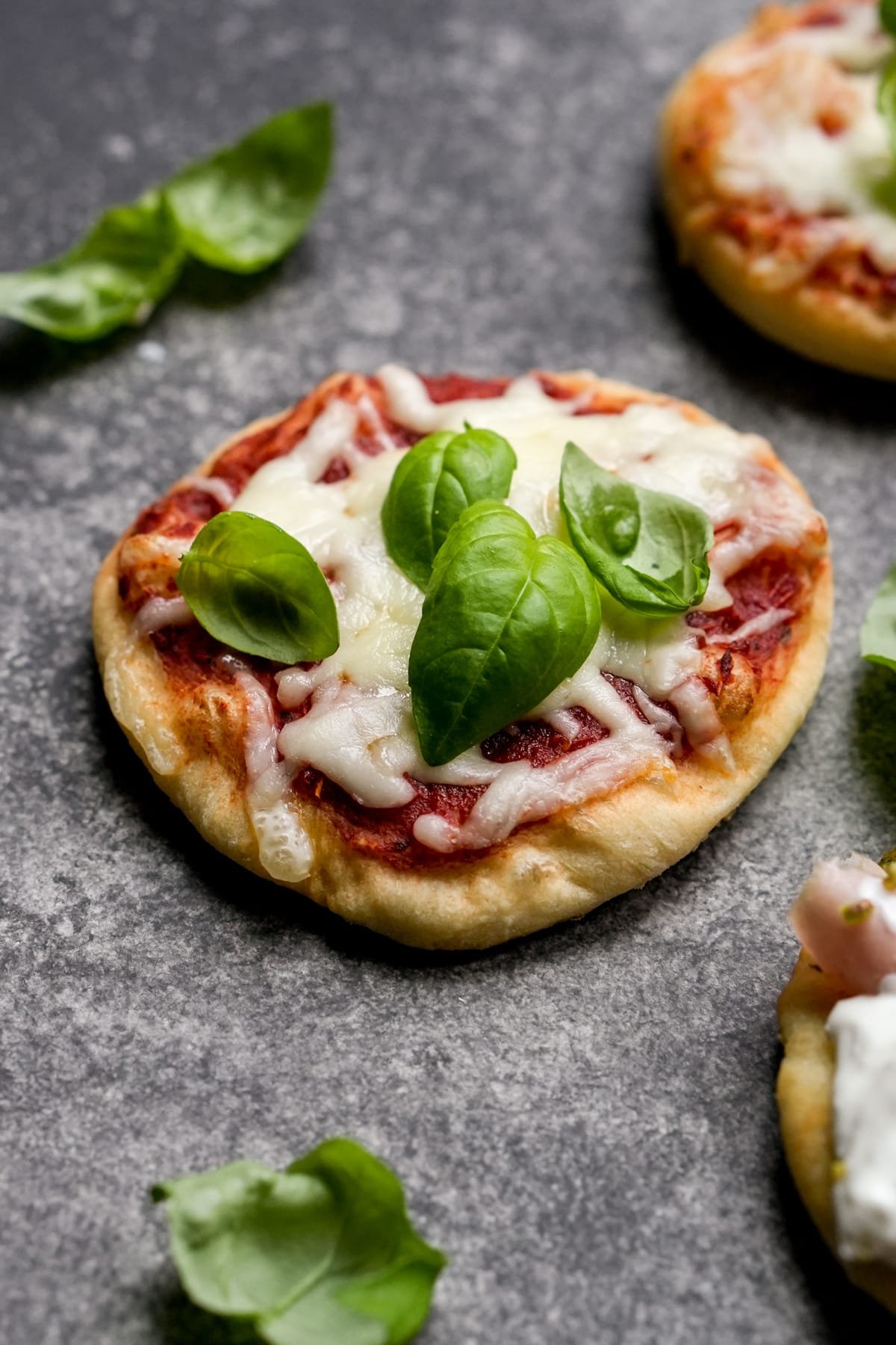 Mini pizzetta topped with pizza sauce, mozzarella and basil