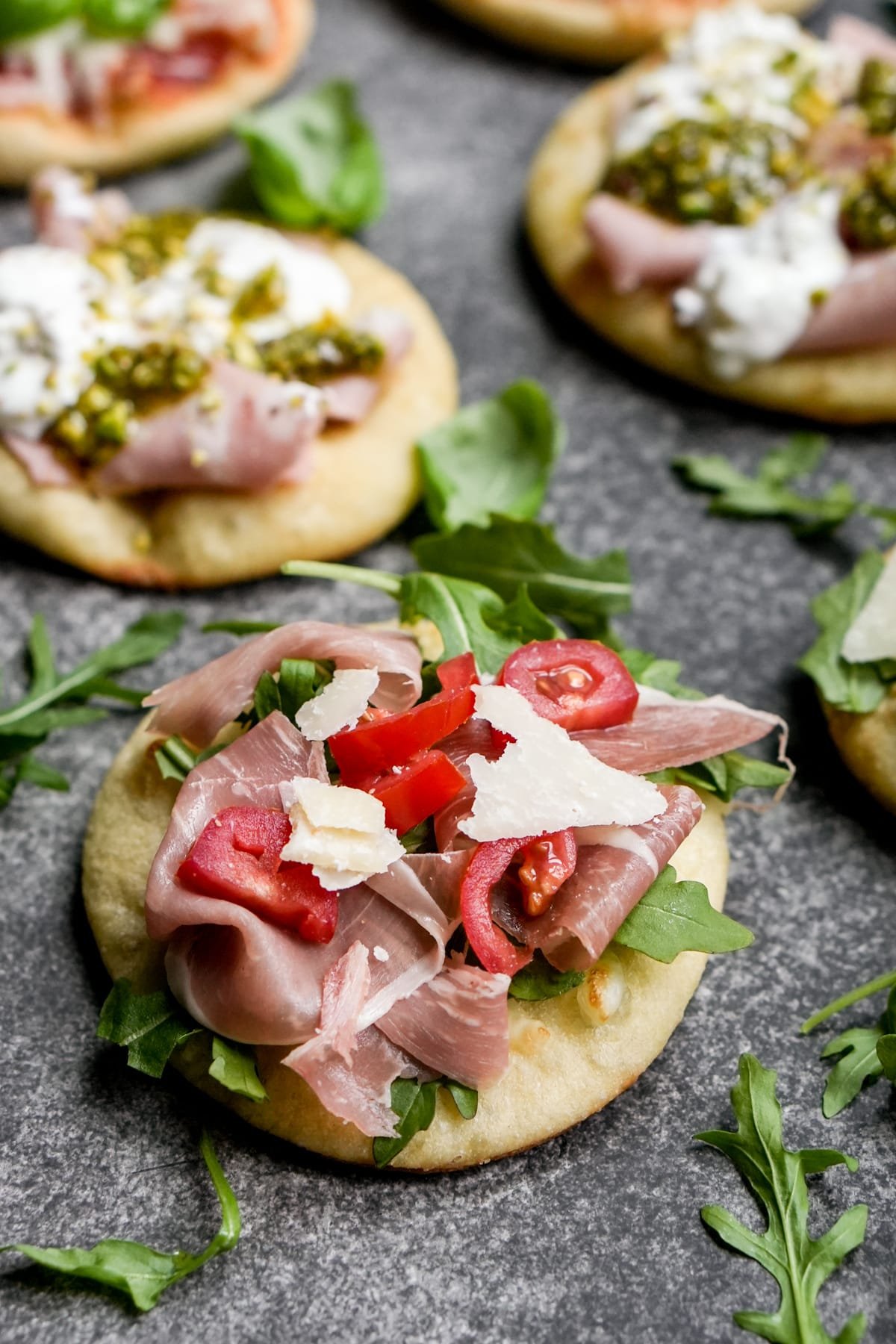 Mini pizzetta topped with prosciutto, arugula, parmigiano and cherry tomatoes