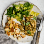 Pesto chicken in a plate with roasted potatoes and salad