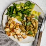 Italian pesto chicken on a dish with roasted potatoes and salad