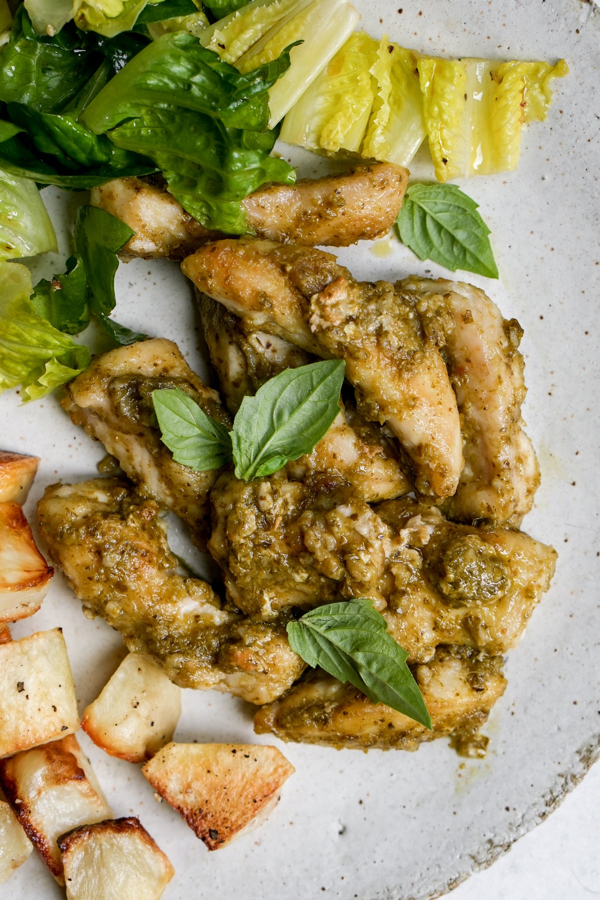 Italian pesto chicken in a plate topped with fresh basil