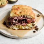 Salami sandwich on a plate on top of parchment paper