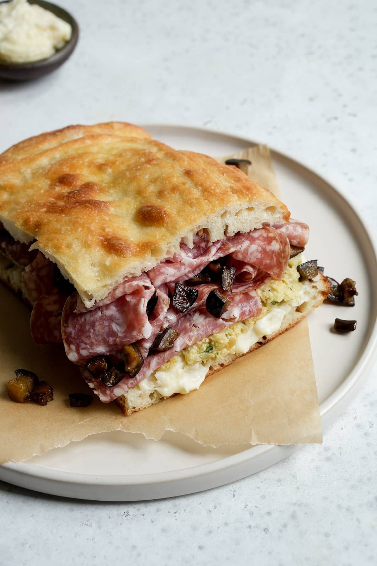 Salami sandwich on a plate with pecorino cream. artichoke spread, salami and spicy eggplant