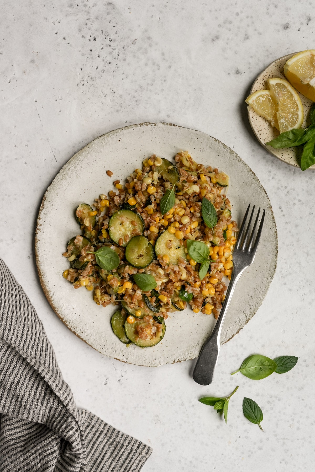 Italian farro salad with zucchini and corn in a plate topped with fresh basil and mint