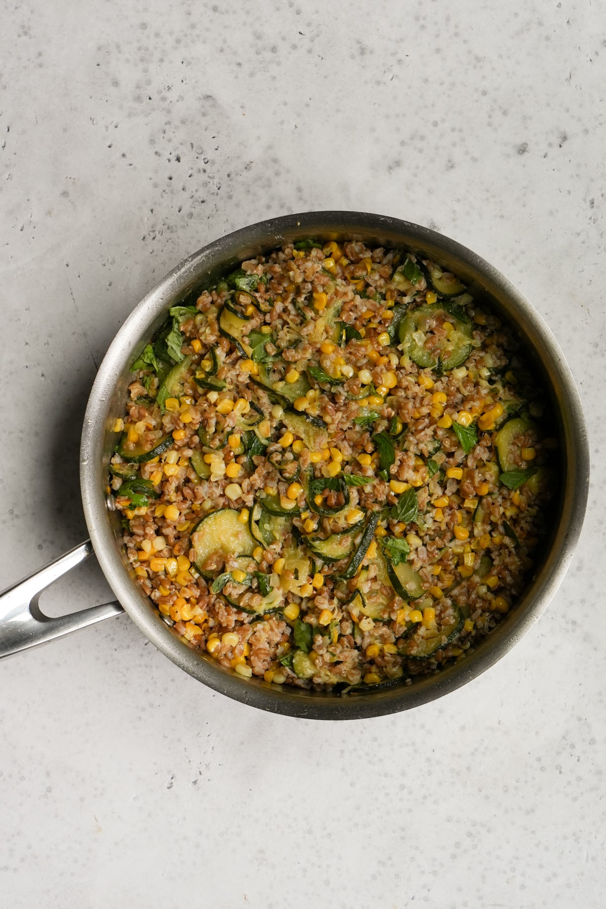 Italian farro salad process - Italian farro in a pan with zucchini and corn