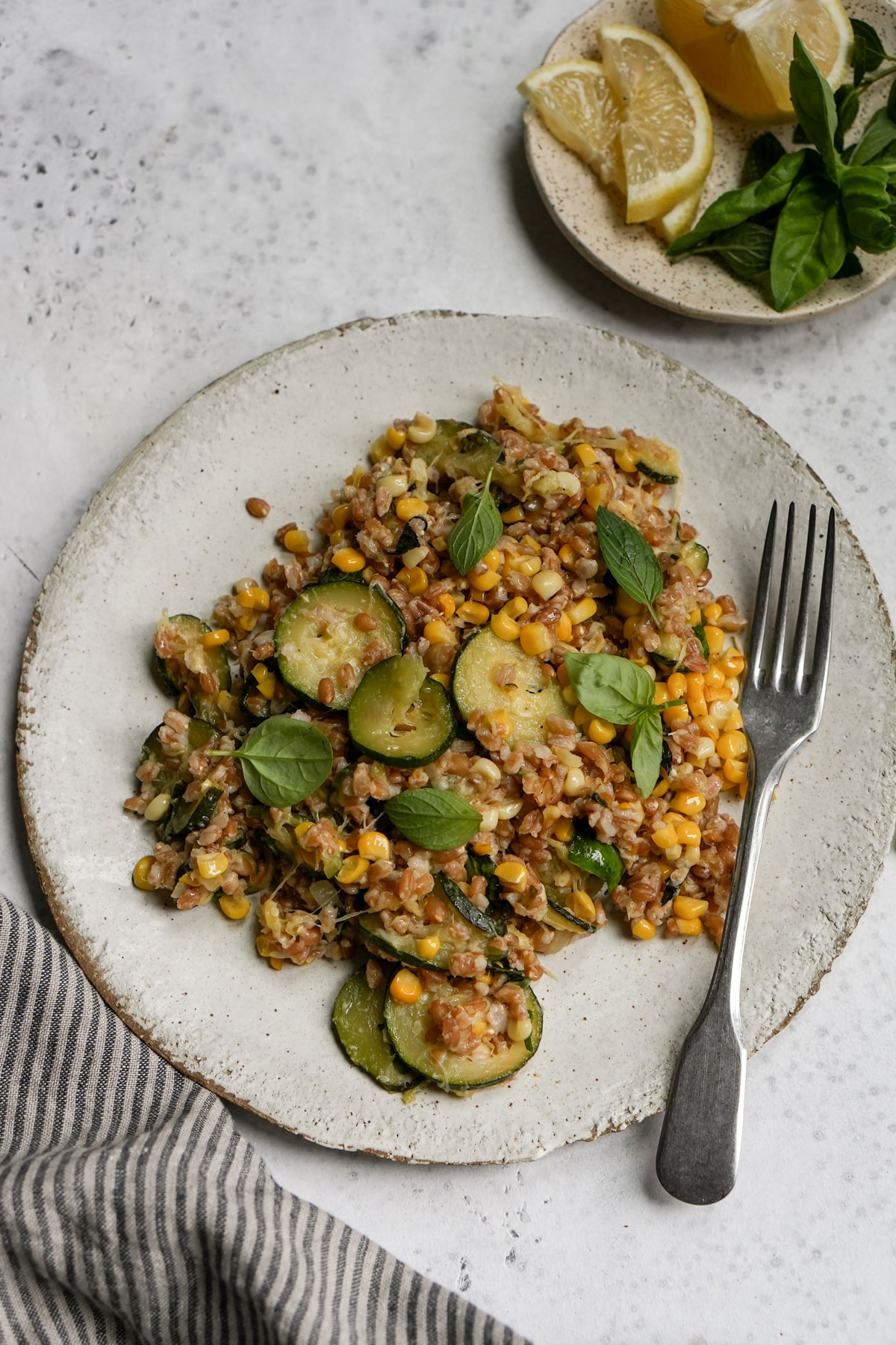 Italian farro salad with zucchini and corn in a plate with a fork to the side
