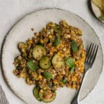 Italian farro salad with corn and zucchini in a plate with a napkin to the side