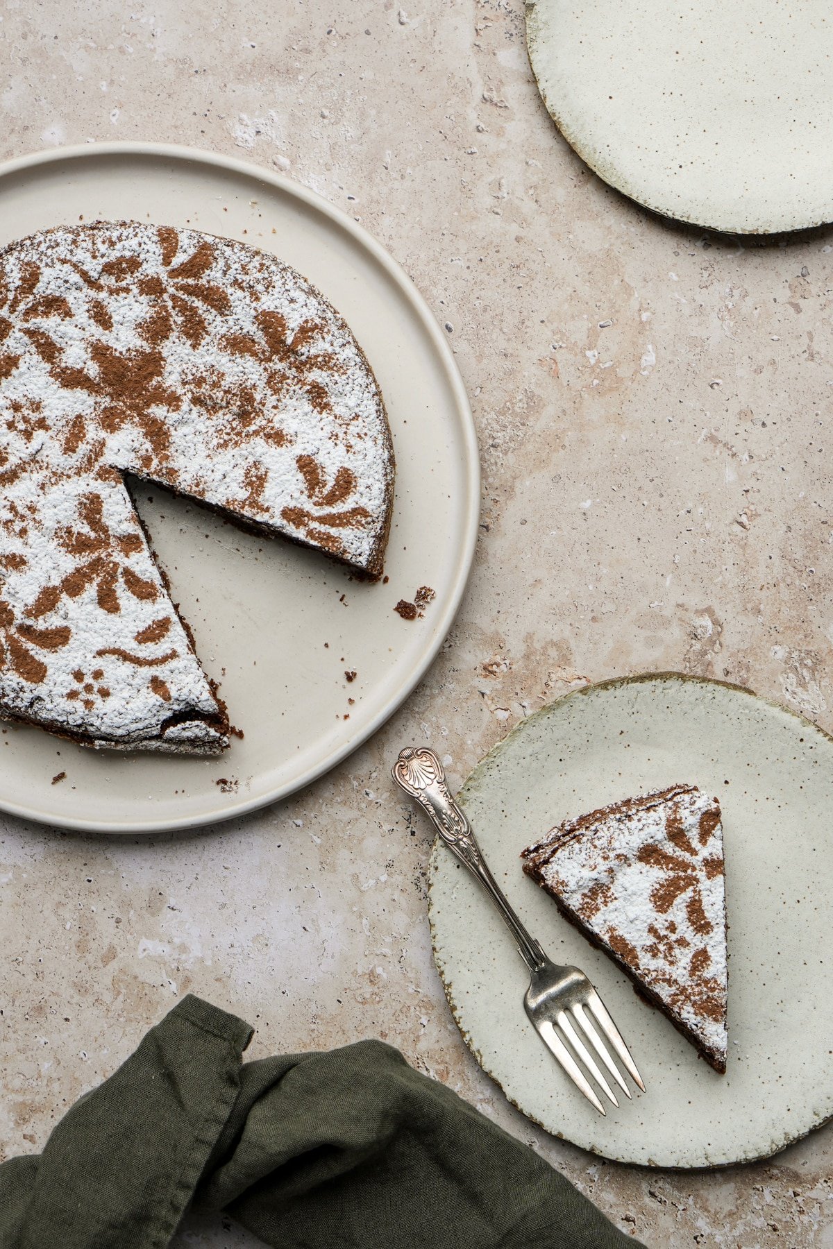 Almond flour chcolate cake in a large plate, with a piece of cake in a small plate