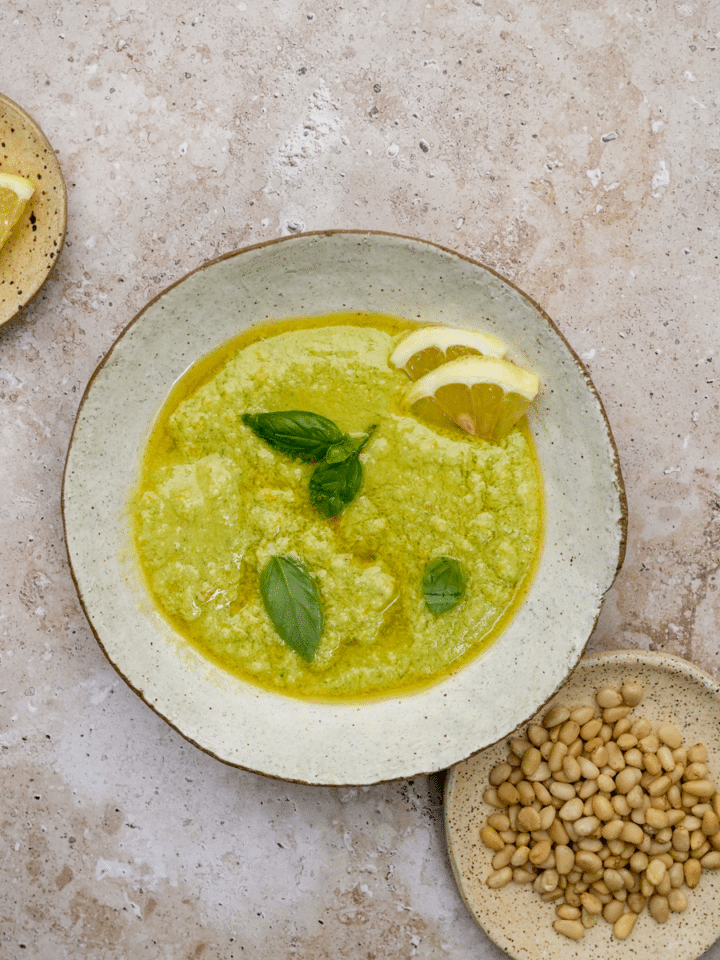 Lemon pesto in a bowl topped with fresh basil and fresh lemons