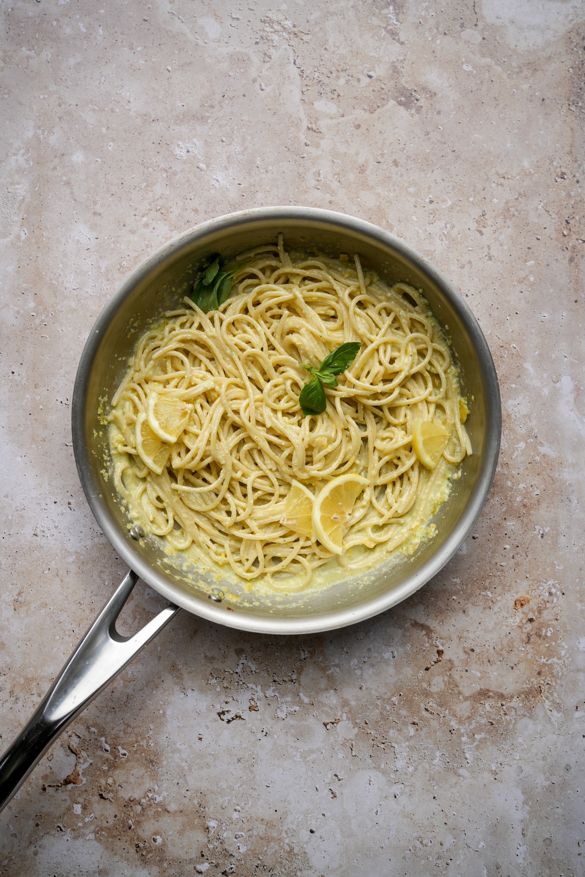 Lemon Pesto pasta in a pan topped with fresh lemons and basil