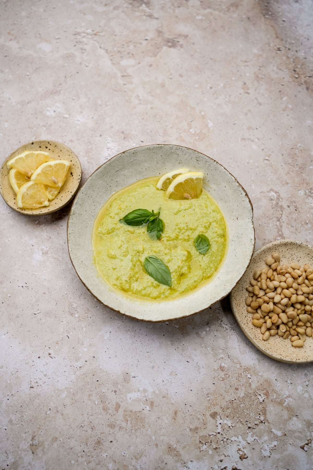 Lemon pesto in a bowl topped with fresh lemons and basil