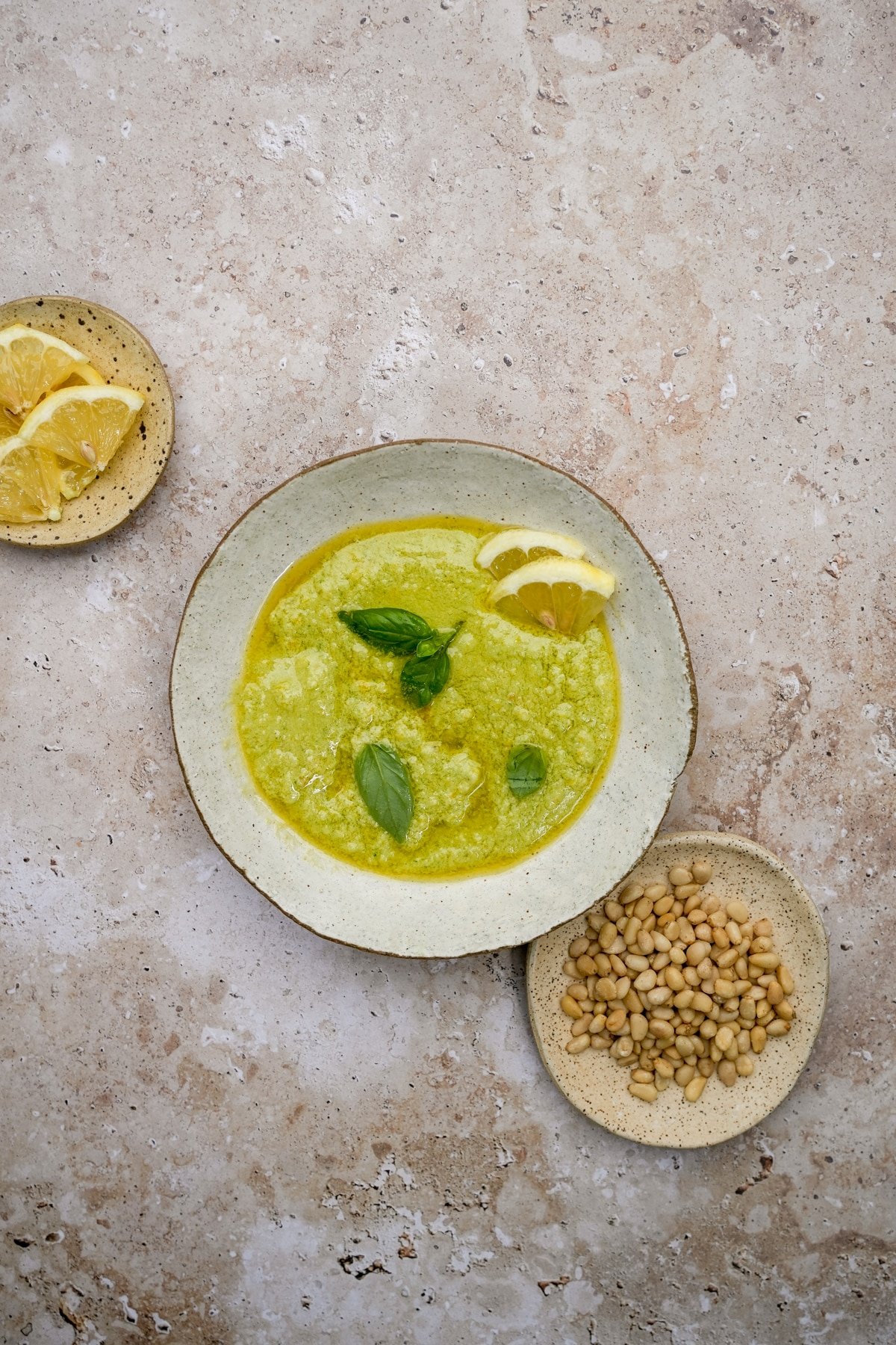 Lemon pesto in a bowl with a small dish of pine nuts to the side