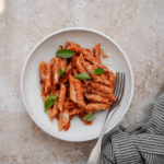 Penne pomodoro in a plate topped with fresh basil