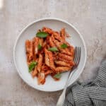 Penne pomodoro in a plate topped with fresh basil