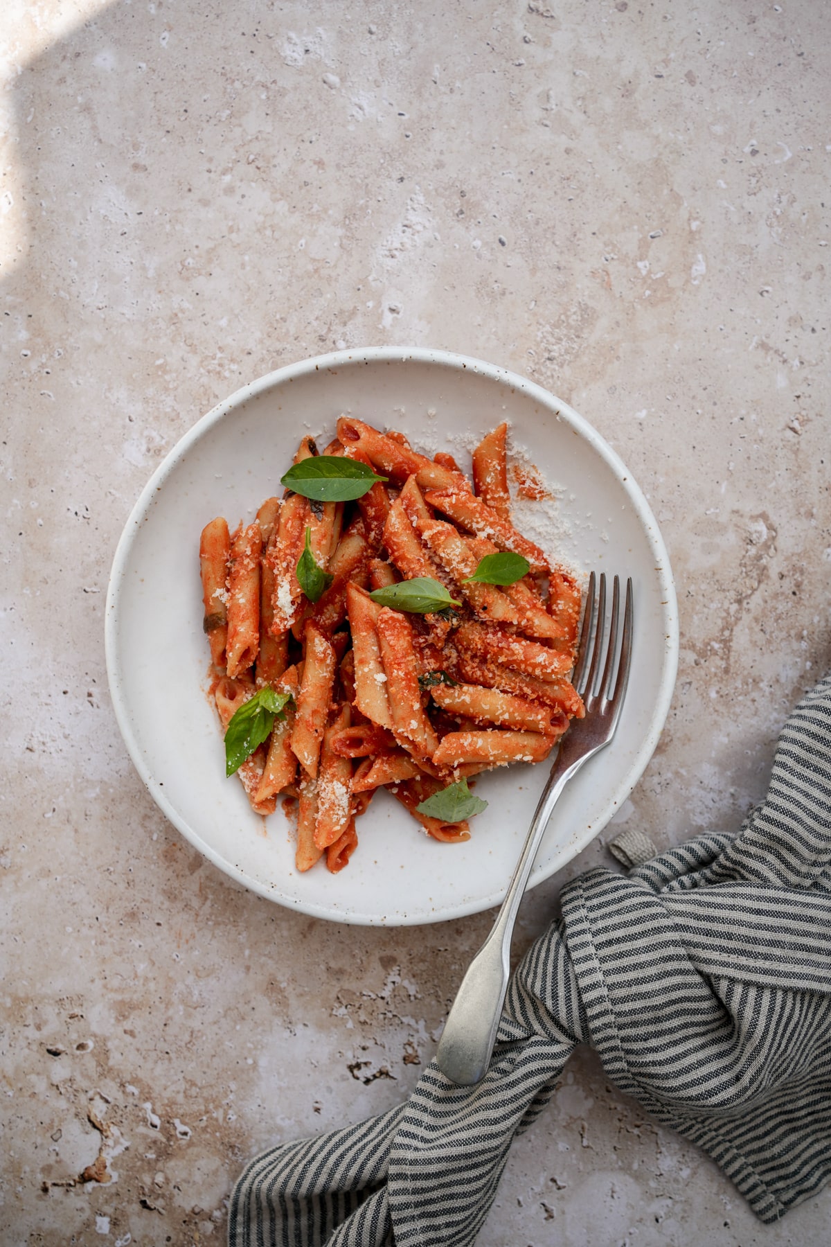 Penne pomodoro in a plate topped with fresh basil